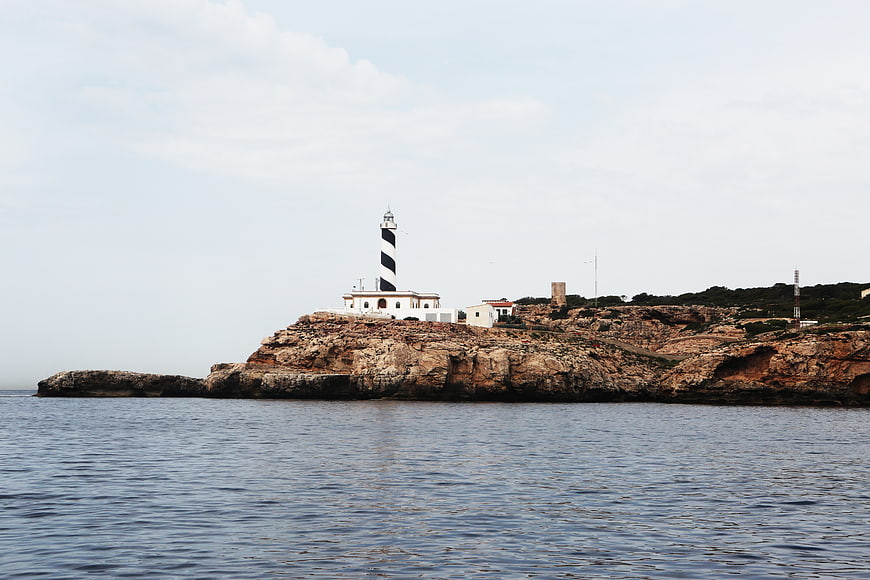 Black and white striped lighthouse on rocky coastal cliff