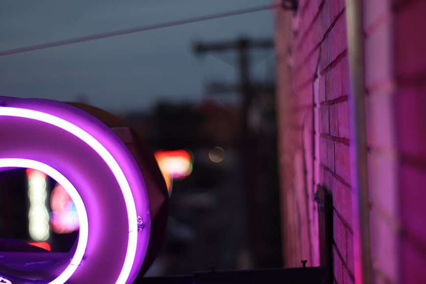 Close-up of purple neon sign on brick wall at night
