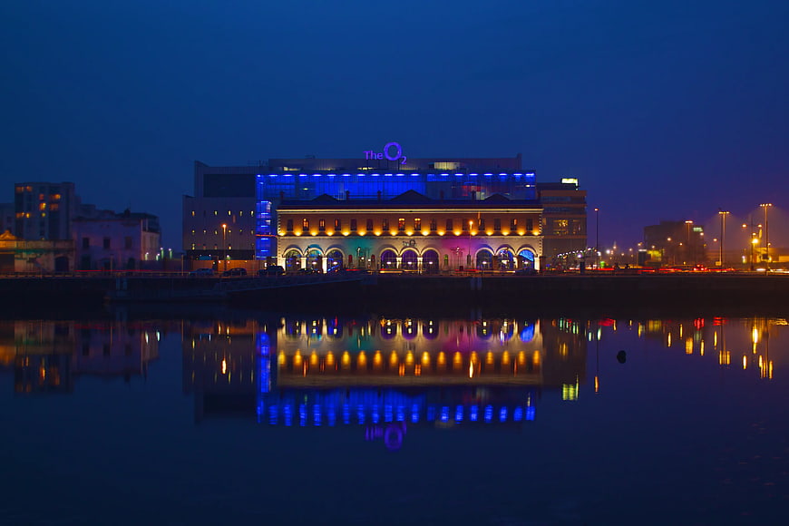 The O2 Arena Dublin illuminated at night with water reflections