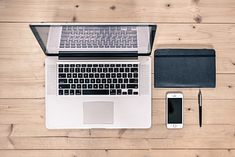Top view of laptop, smartphone, and notebook on wooden desk