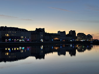 European city skyline at dusk with calm water reflections