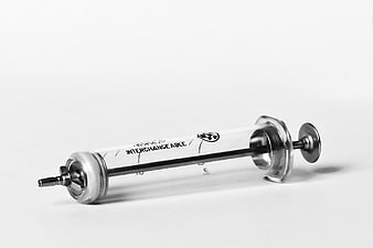 Vintage medical syringe with metal plunger on white background