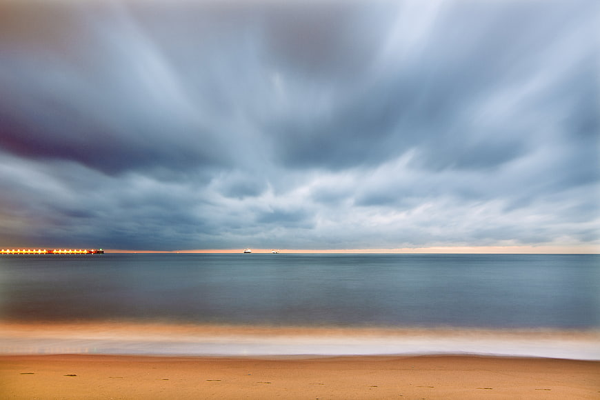 Long Exposure Stormy Sky Over Calm Ocean Beach at Sunset