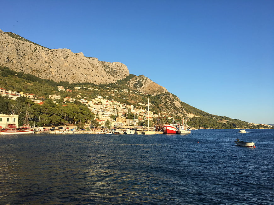 Coastal Town Harbor with Boats and Mountain Backdrop