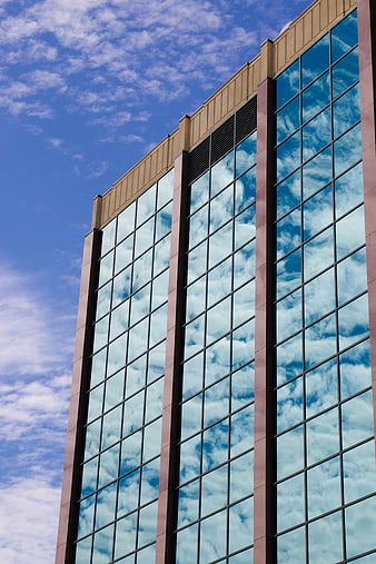 Modern Glass Skyscraper Reflecting Blue Sky and Clouds