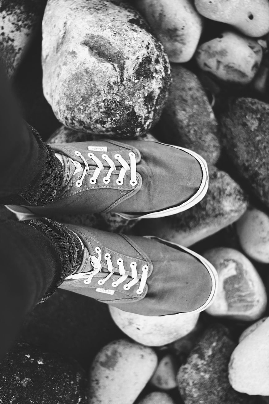 Black and white sneakers on smooth river stones