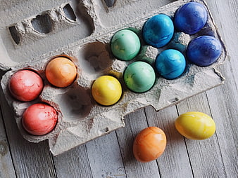 Colorful Easter Eggs in Cardboard Carton on Wooden Table