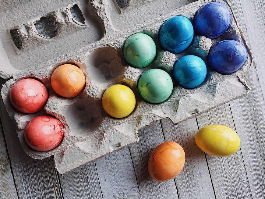 Colorful Easter Eggs in Cardboard Carton on Wooden Table