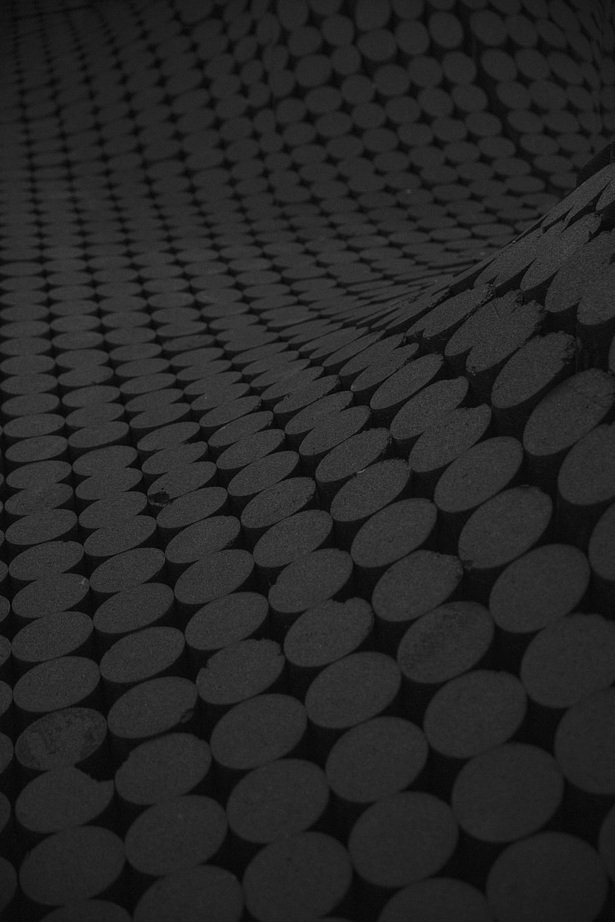 Dark abstract pattern of stacked cylindrical logs in monochrome