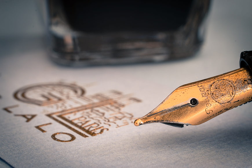 Close-up of vintage gold fountain pen nib on paper