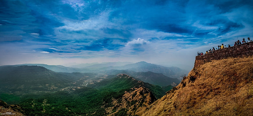 Panoramic mountain landscape with tourists on a cliff viewpoint