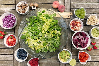 Overhead view of fresh salad ingredients and fruits on wooden table