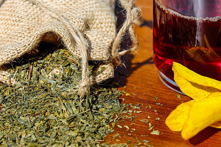 Dried herbs spilling from burlap sack next to red tea