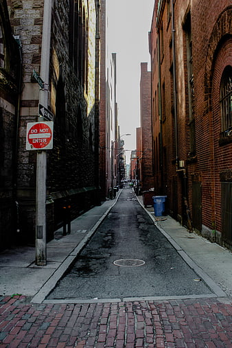 Narrow brick alleyway in urban city with do not enter sign