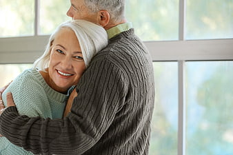 Happy Senior Couple Hugging Indoors by Window