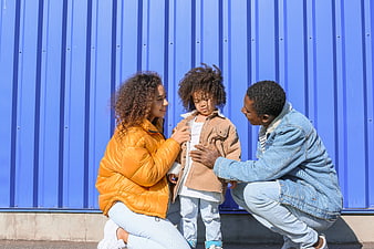 Happy Black Family Helping Child With Jacket Against Blue Wall