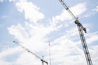 Construction Cranes Against Blue Sky with Clouds