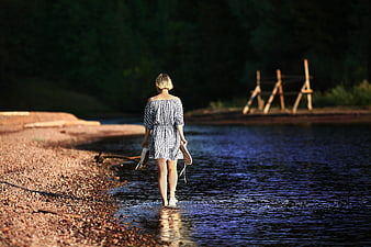 Woman Walking Barefoot in River at Sunset
