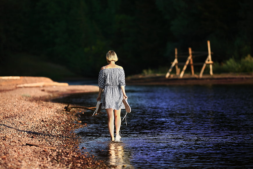 Woman Walking Barefoot in River at Sunset