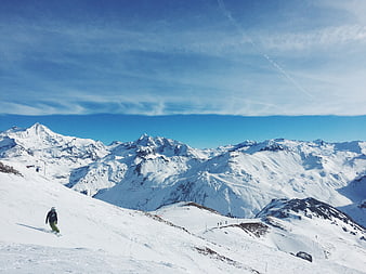 Snowboarder on Alpine Slope with Mountain Peaks