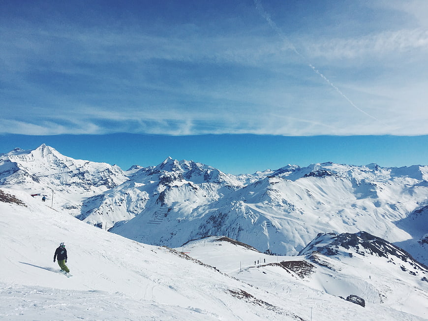 Snowboarder on Alpine Slope with Mountain Peaks