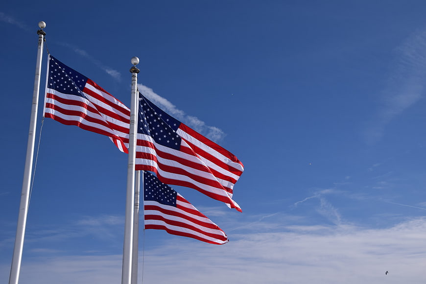 Three American Flags Waving Against Blue Sky