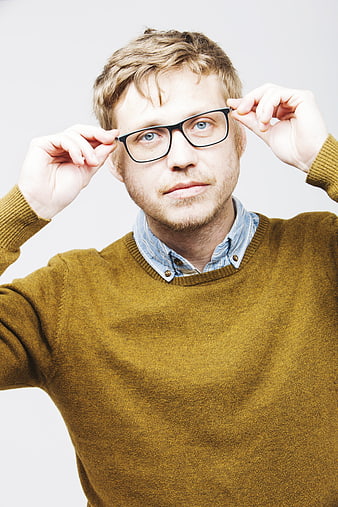 Portrait of young man with glasses and beard adjusting spectacles
