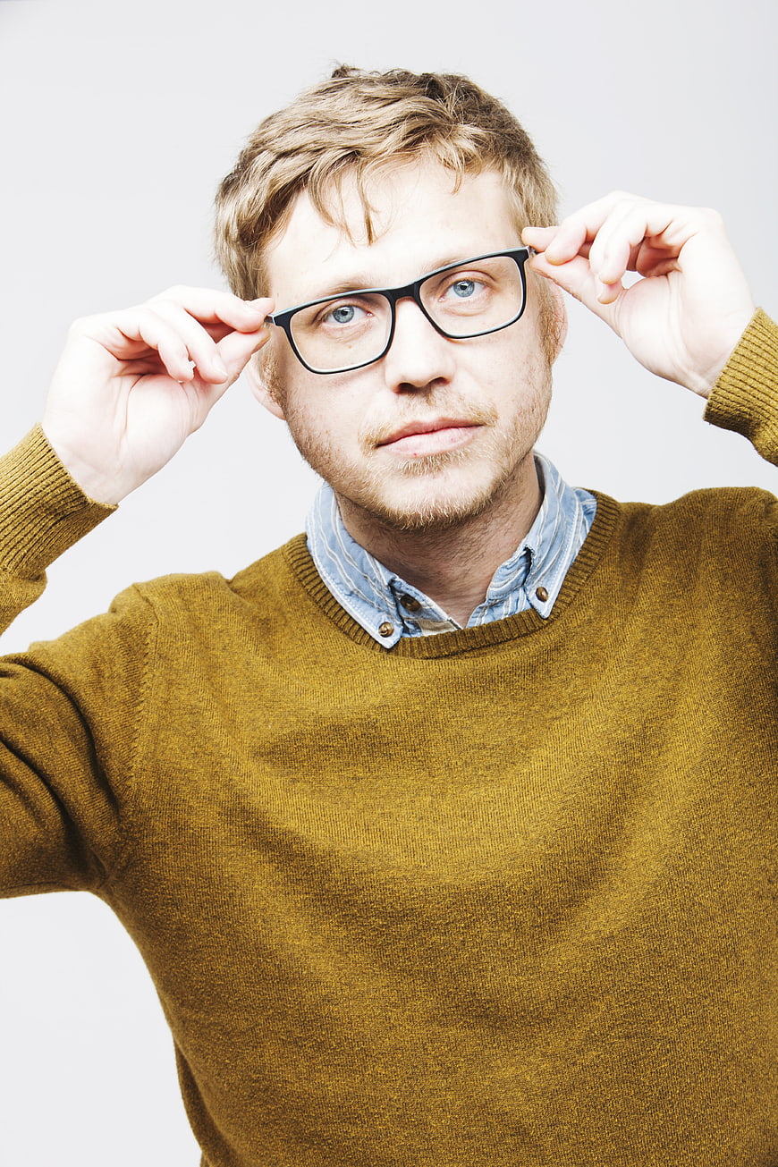Portrait of young man with glasses and beard adjusting spectacles