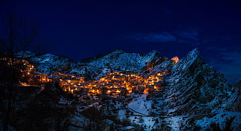 Illuminated Italian Mountain Village in Winter Snow at Night