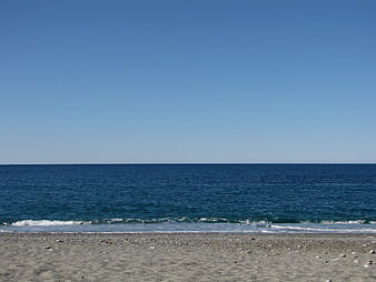 Serene pebble beach with deep blue ocean and clear sky