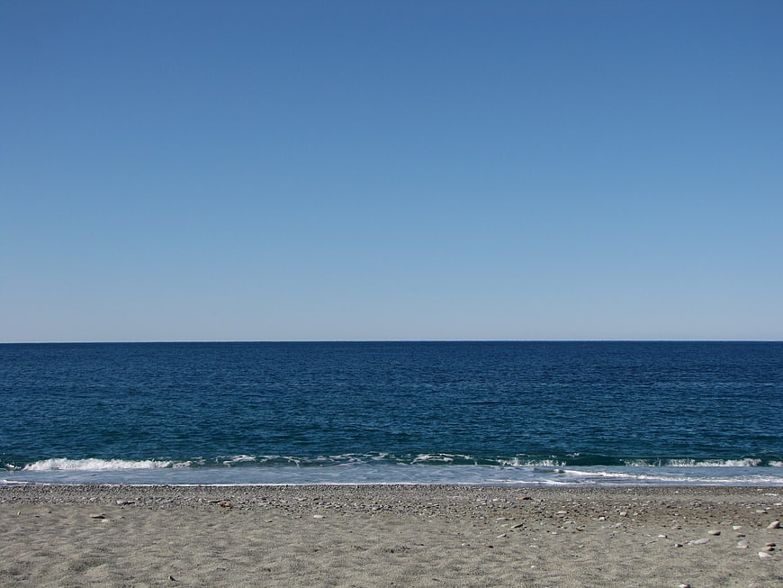 Serene pebble beach with deep blue ocean and clear sky