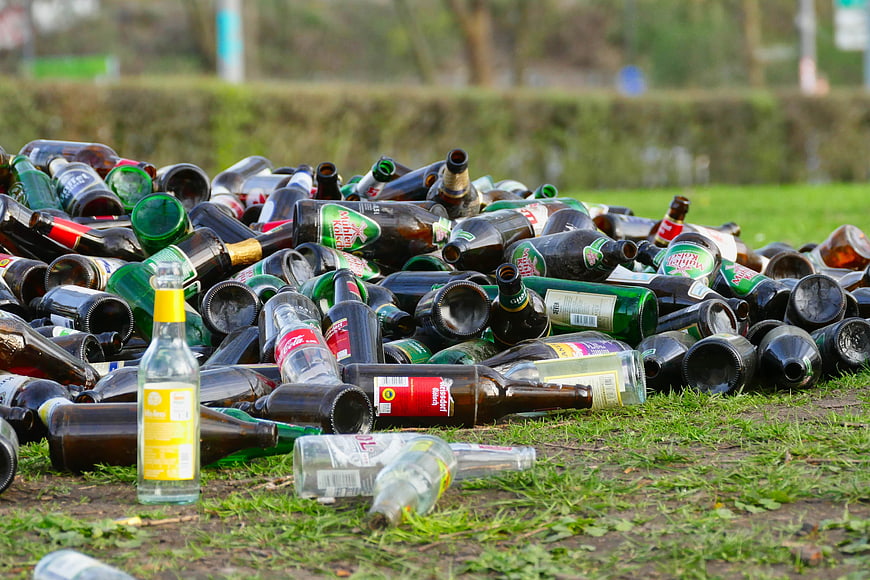 Pile of discarded glass bottles on grass