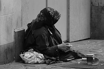 Black and white photo of a woman sitting on a cobblestone street
