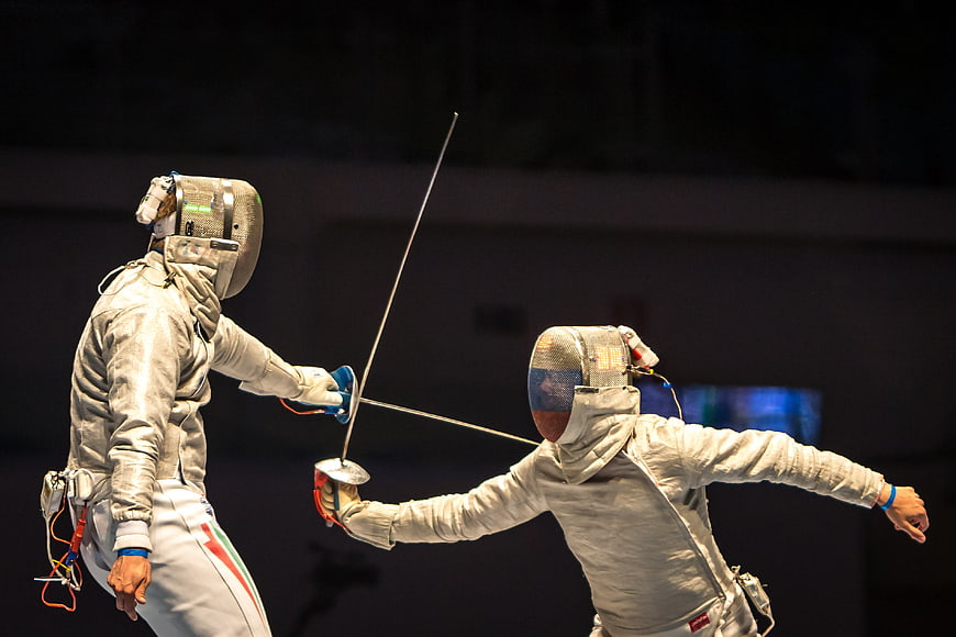 Two Fencers Competing in Intense Indoor Sports Match