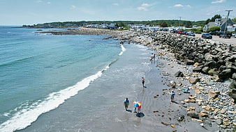 Aerial View of Rocky Beach with People Walking Near Ocean