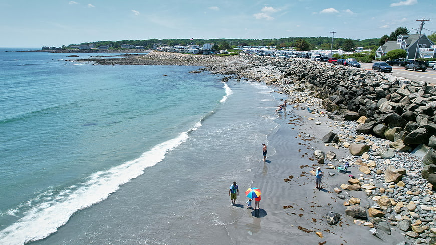 Aerial View of Rocky Beach with People Walking Near Ocean