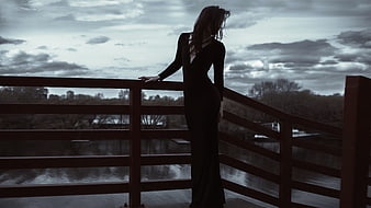 Silhouette of a woman in a long dress standing on a bridge
