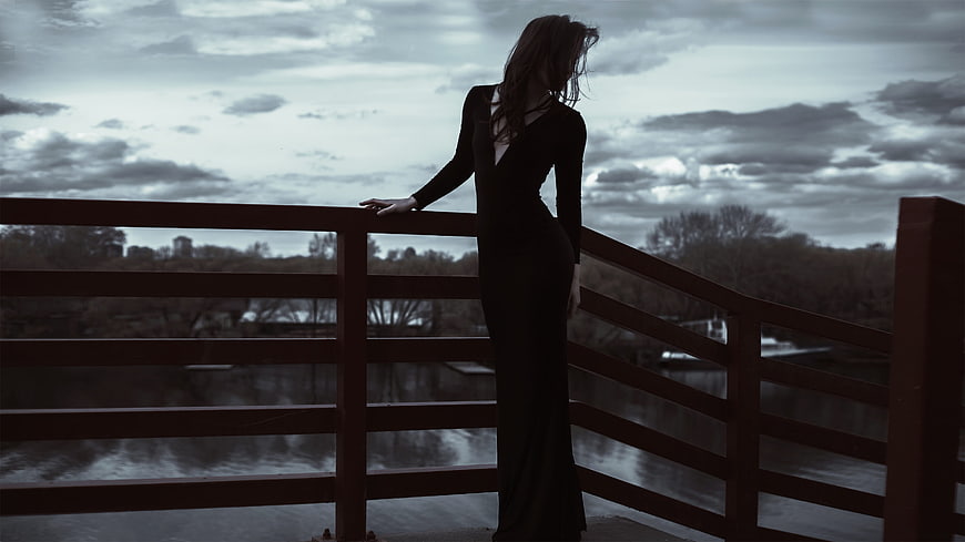 Silhouette of a woman in a long dress standing on a bridge