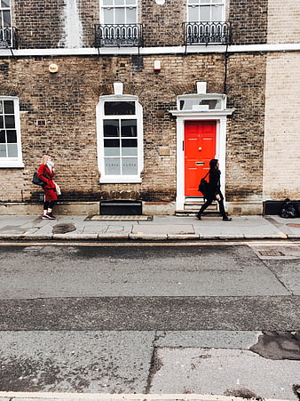 Red door on London brick building with pedestrians