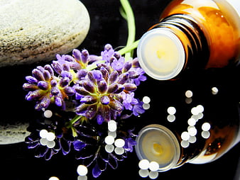 Lavender flowers, essential oil bottle, and homeopathic globules on black