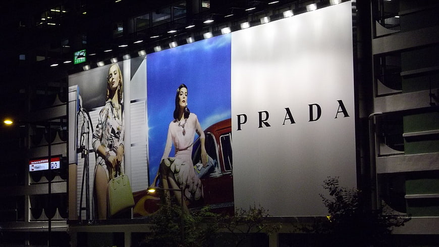 Large Prada fashion billboard advertisement on urban building at night