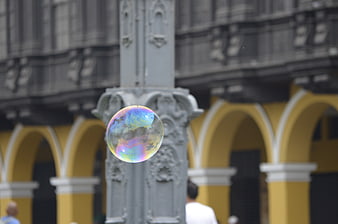 Iridescent soap bubble floating in front of colonial architecture