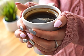 Woman holding coffee cup with pink and silver manicure