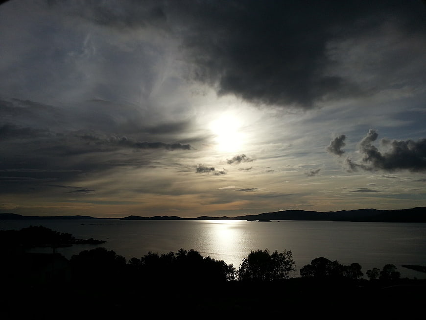 Dramatic Sunlight Breaking Through Storm Clouds Over Fjord