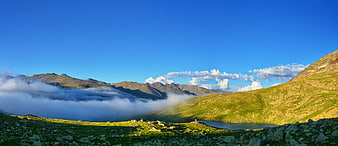 Panoramic mountain landscape with misty valley and alpine lake