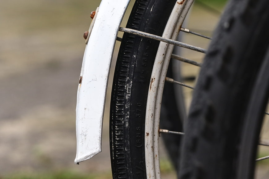Close-up of rusty bicycle wheel with white fender