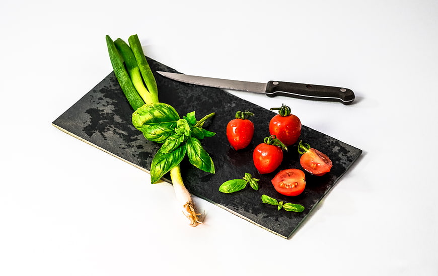Fresh vegetables and knife on black slate board