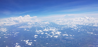 Aerial view of fluffy white clouds over blue landscape