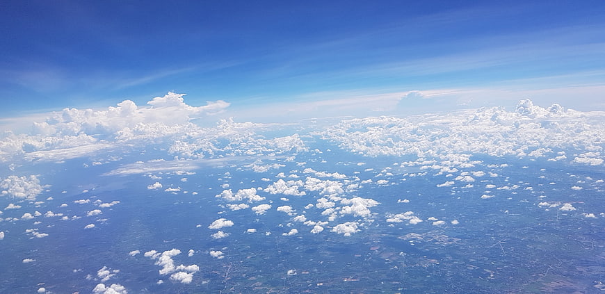 Aerial view of fluffy white clouds over blue landscape