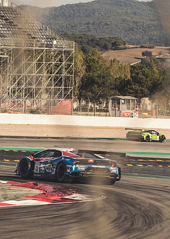 Blue racing car drifting on track with green car in background